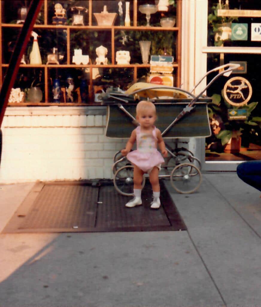 baby standing in front of flower shop